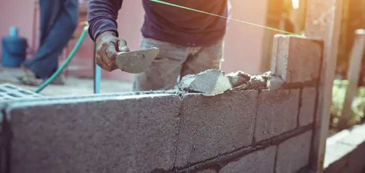 Muro de de un hogar fabricado con blocks de concreto recibiendo una capa de recubrimiento