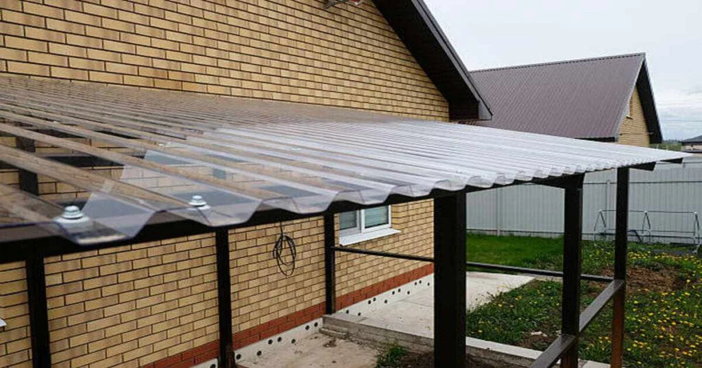 Espacio de servicio exterior con lámina de policarbonato translúcida instalada sobre estructura ligera