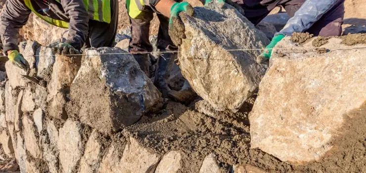 Trabajadores realizando la construcción de un muro de piedra de una casa