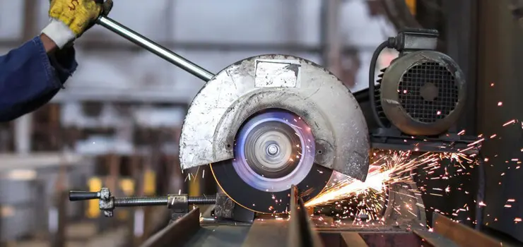 Herrero empleando cortadora de metal de mesa