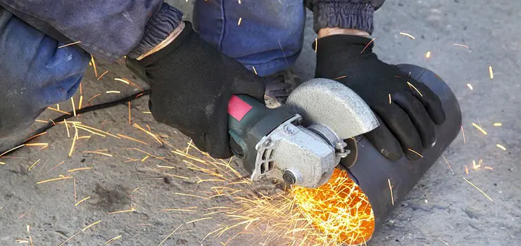 Persona cortando pieza de metal cilíndrica