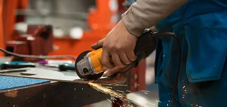 Herrero utilizando una amoladora sobre una pieza de metal en una herrería