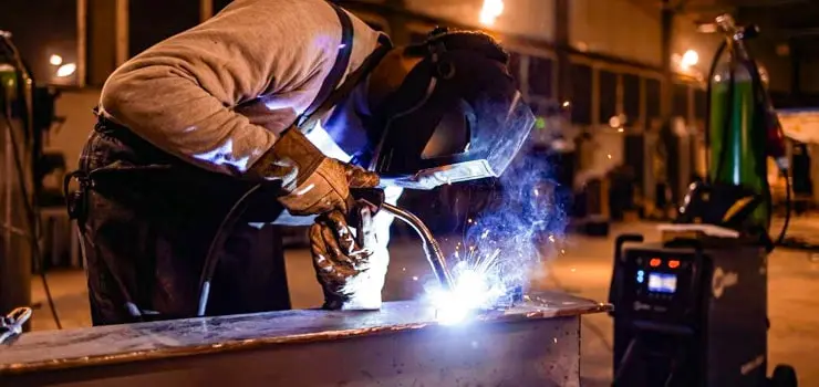 Persona utilizando una máquina soldadora para llevar a cabo un trabajo de herrería