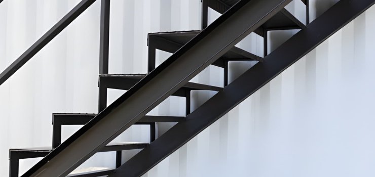 Detalle de escalera de herrería recta y negra fabricada con perfiles y lámina de acero