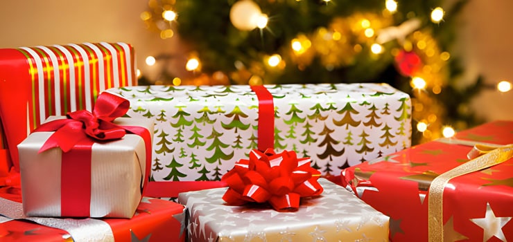 Árbol decorado con adornos de Navidad, regalos y series de luces en habitación