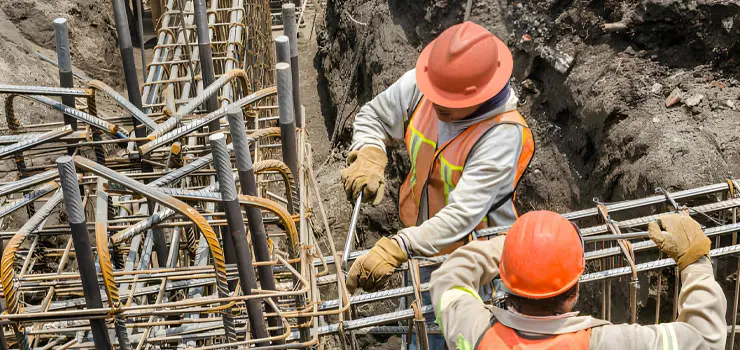 Trabajadores de la construcción armando cimientos con acero de refuerzo
