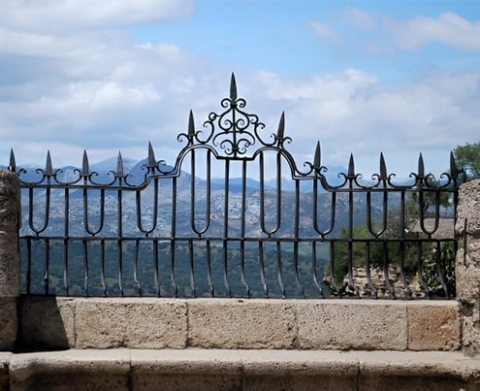 Barda de piedra y concreto con decoración de herrería con picos