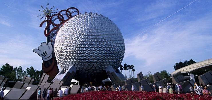 Esfera geodésica de aluminio frente a personas y jardín de flores rojas