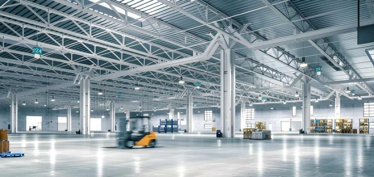 Interior de nave industrial mixta con muros de concreto y columnas, armaduras y techo de acero